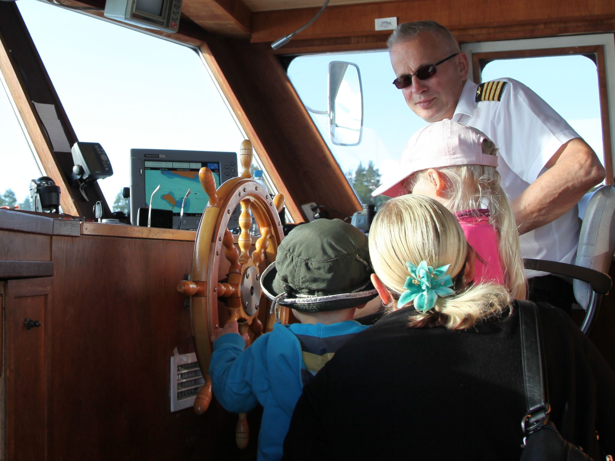 Pikkukippari-risteilyllä lapsi ohjaa venettä kapteenin kanssa Bellanrannan edustalla